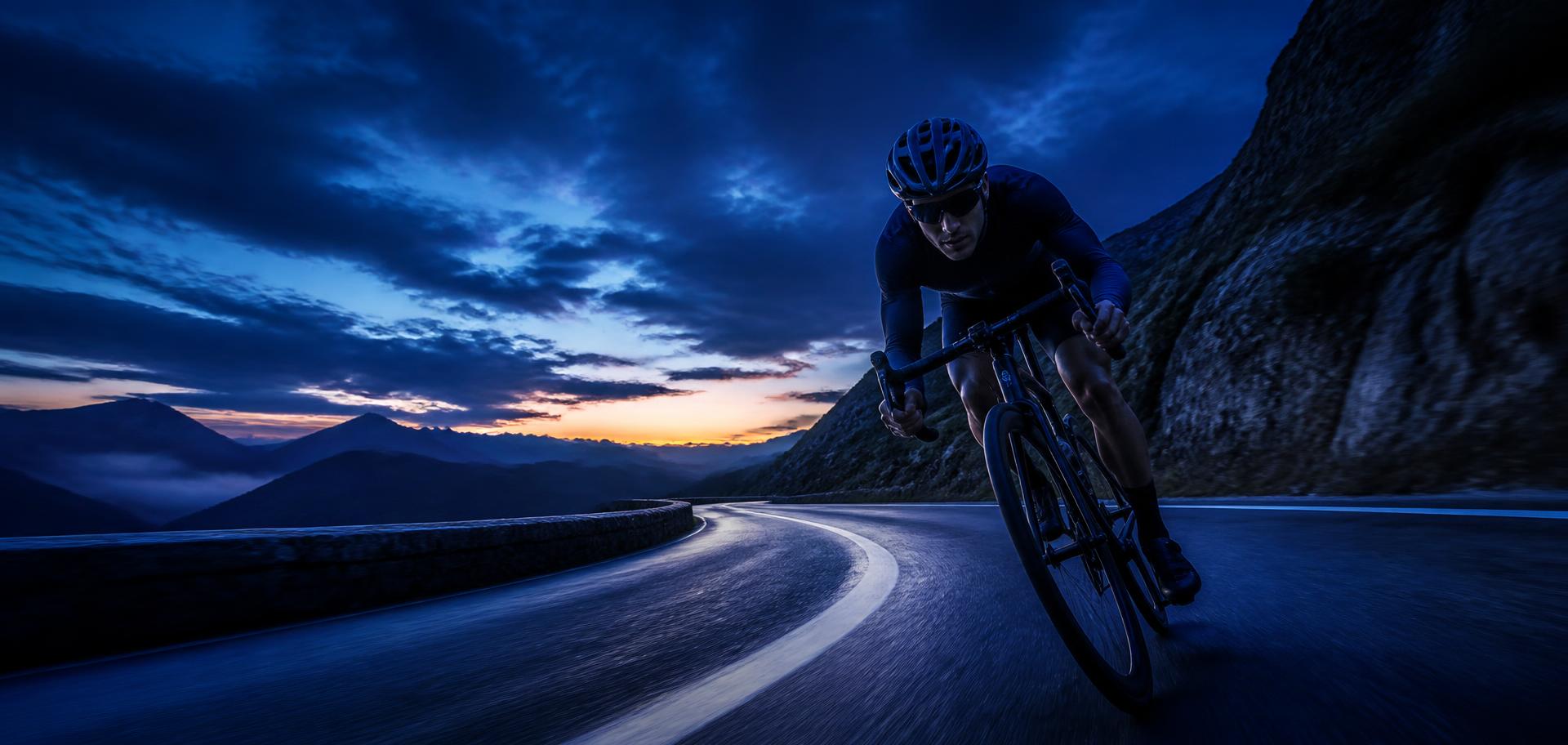 Cyclist riding a mountain road at dawn